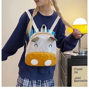 Nahaufnahme des süßen Comic-Kuh-Schulrucksacks an einem Modell in gemütlicher Umgebung