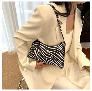 Detail shot of a stylish zebra-print shoulder bag styled with a minimalist cream blazer.