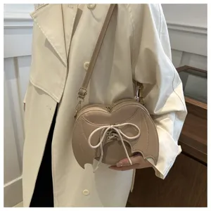 Detail van beige hartvormige crossbodytas met gotische vleermuisvleugels en veters.
