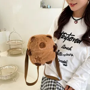 Gros plan d'un sac à bandoulière en peluche capybara marron porté par un mannequin.