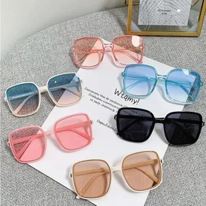 Overhead view of multiple oversized square sunglasses in varied colors on white paper