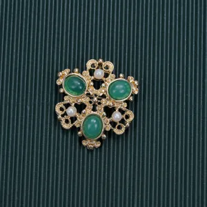High-detail view of a vintage Baroque style brooch with green cabochons and pearls