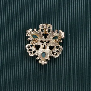 Detailed back view of a gold Baroque style brooch on a green ribbed background