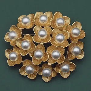 Nahaufnahme einer goldenen Blumenkranz-Brosche im Vintage-Stil mit eleganten weißen Perlen