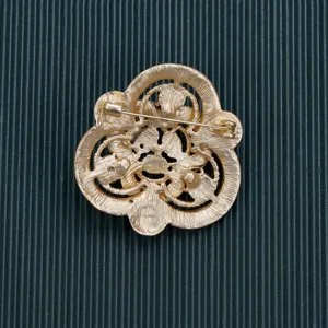 Detailed back view of a gold-toned baroque style brooch showing the pin mechanism