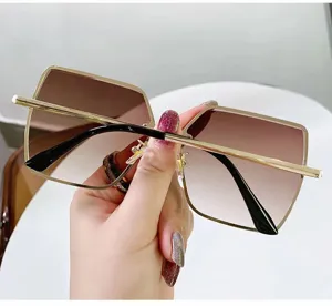 Hand hält stylische quadratische randlose Sonnenbrille mit braunem Farbverlauf und Goldbügeln