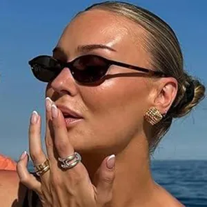 Gros plan sur des lunettes de soleil ovales à la mode portées par un mannequin en bord de mer