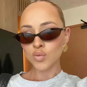 Gros plan de lunettes de soleil ovales élégantes avec monture noire sur un mannequin.