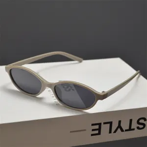 Vue détaillée de lunettes de soleil ovales kaki sur une boîte blanche minimaliste