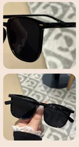 Detailed view of stylish black square frame sunglasses held by hand in lifestyle setting