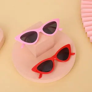 Retro cat-eye sunglasses in stylish pink and red colors displayed on geometric props.