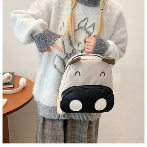 Detailansicht eines süßen Kuh-Rucksacks für Kinder, gehalten von einer Schülerin