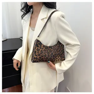 Close-up detail of a trendy leopard print baguette bag held by model in white blazer
