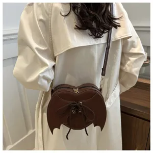 Detailweergave van de hartvormige crossbodytas met vleermuisvleugels in bruin leer