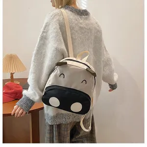 Detaillierte Ansicht des süßen Cartoon-Kuh-Rucksacks, getragen von einem Modell im Haus