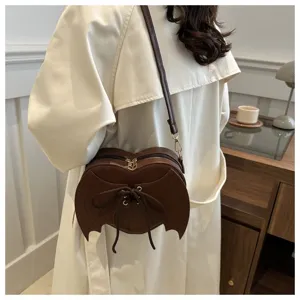 Gedetailleerd overzicht van een hartvormige crossbodytas met vleermuisvleugelontwerp op model