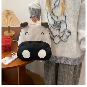 Süßer Kinderrucksack im Kuh-Design, von einem Model in gemütlichem Heim getragen