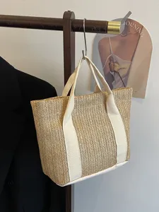 Primer plano de la textura de paja natural y las asas color crema de este bolso de playa.