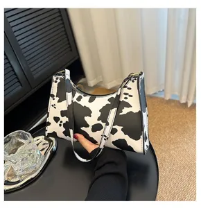 Trendy black and white cow print underarm bag for women, stylish retro shoulder bag view.