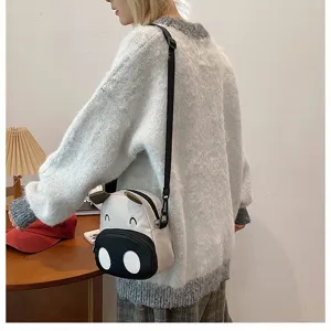 Süße Cartoon-Kuh Umhängetasche, getragen von einem Modell in einem grauen Strickpullover
