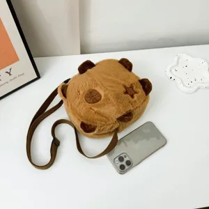 Détail d'un sac bandoulière en peluche capybara marron avec un smartphone pour l'échelle
