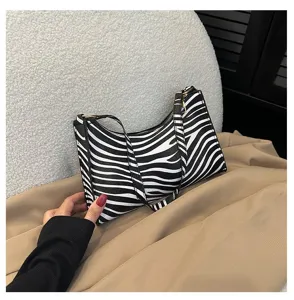 Detailed view of a fashionable zebra print underarm bag placed on a neutral fabric backdrop