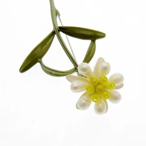 Detailed close-up of vintage green lacquered carnation flower brooch with pearl-like petals