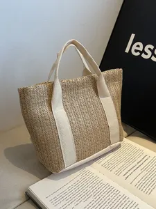 Detalle de bolso de paja tejida con asas de lona crema y patrón de textura trenzada