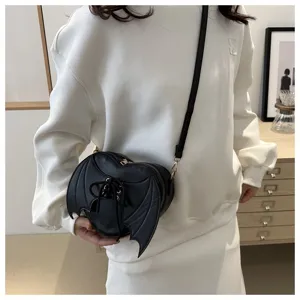 Zwarte hartvormige crossbodytas met vleermuisvleugels getoond op een model in een lifestyle-foto