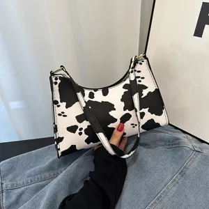 Close-up of stylish cow-print underarm bag featuring black and white patterns.