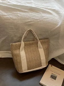 Detalle de un bolso capazo de paja hecho a mano con asas de tela crema para la playa
