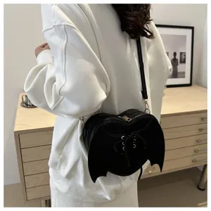 Gotische zwarte hartvormige crossbodytas met vleermuisvleugels gedragen door een model