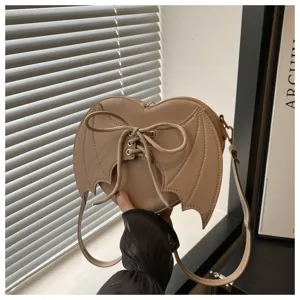 Hartvormige beige crossbody tas met vleermuisvleugels en vetersluiting met strik