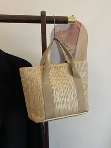 Bolso tote de paja natural con asas de lona colgado para un estilo de verano chic.