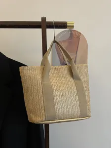 Vista detallada de un bolso de paja trenzada colgado en un perchero de madera minimalista.