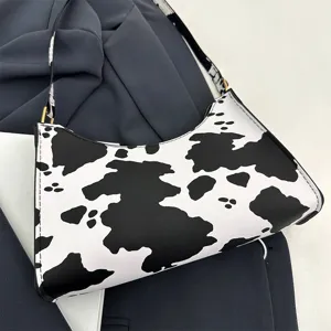 Close-up of stylish cow print shoulder bag on navy blue fabric background