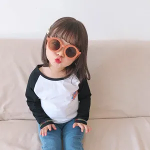 Adorable niña modelo con elegantes gafas de sol redondas naranja mate y protección UV400