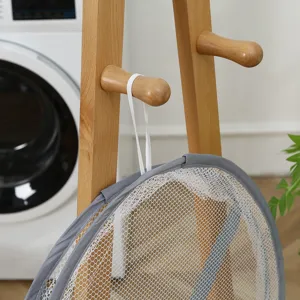 Close-up detail of a gray foldable mesh laundry drying net hanging on a wooden rack