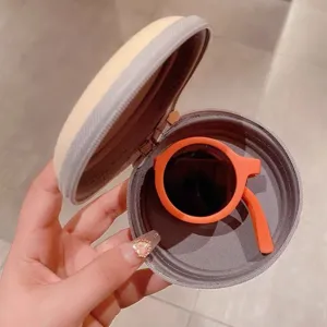 Detailansicht faltbare orangefarbene runde Kindersonnenbrille in beiger Tasche