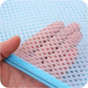 Macro detail of breathable white mesh material on a portable blue laundry basket.
