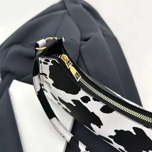 Macro view showing the gold zipper and cow print texture of this stylish shoulder bag.