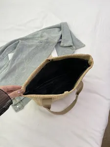 Vista detallada del forro interior negro y el cierre magnético de un bolso de paja