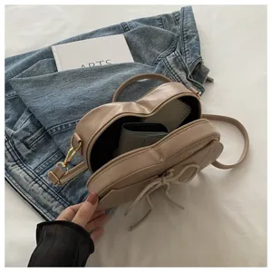 Gedetailleerd binnenaanzicht van een beige hartvormige crossbodytas met een strik