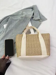 Bolso de paja tejida con asas crema y un teléfono inteligente para escala de tamaño
