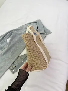Primer plano de bolso tote de paja con correas de lona blanca sobre denim
