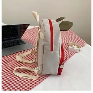 Seitenansicht eines niedlichen Kinderrucksacks im Kuh-Design mit roten Akzenten.