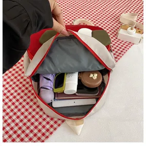 Innenansicht des niedlichen roten Kuh-Kinderrucksacks, gefüllt mit wichtigen Utensilien