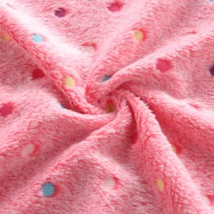 Soft pink fleece blanket fabric close-up with colorful polka dots, fluffy texture detail.