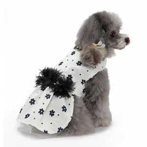 Vue rapprochée des détails de la robe pour chien à imprimé floral noir et pompons.