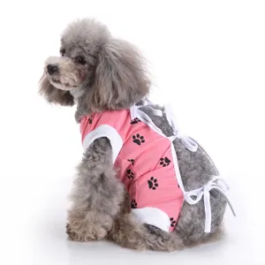 Breathable pink dog surgical recovery suit with cute black paw prints and secure white ties.